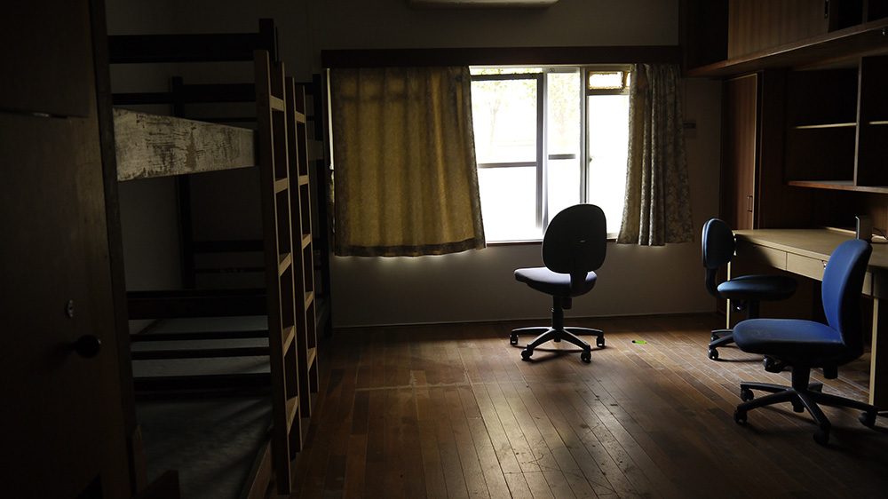 宿舍房間內部，有兩張上下舖床和三張書桌椅子。最多可以住三個人。